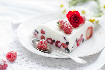 Dessert of yogurt , berries and gelatin, decorated with raw raspberries and natural red rose in white background, fresh, healthy food  