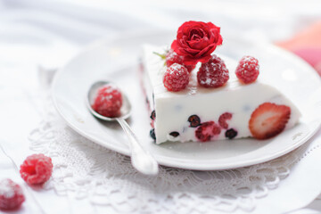 Dessert of yogurt , berries and gelatin, decorated with raw raspberries and natural red rose in white background, fresh, healthy food  