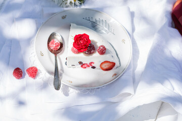 Obraz na płótnie Canvas Homemade dessert of yogurt , berries and gelatin, decorated with raw raspberries and natural red rose in white background in the garden, outdoors, fresh, healthy food 