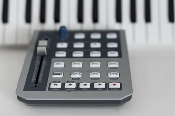 Closeup of an daw (digital audio workstation) controller on a table with piano keys on the...
