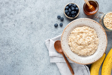 Obraz na płótnie Canvas Breakfast Food Oatmeal Porridge Bowl Served With Fruits And Honey On Concrete Background. Top View Copy Space For Text Recipe Or Design