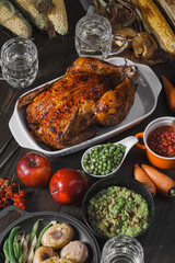 baked chicken and baked corn. family dinner table. baked chicken and vegetables with glasses of cider. delicious rustic dinner