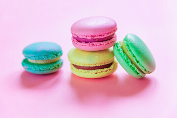 Sweet almond colorful pink blue yellow green macaron or macaroon dessert cake isolated on trendy pink pastel background. French sweet cookie. Minimal food bakery concept. Flat lay top view, copy space