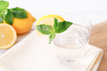Full glass of fresh cool transparent water with lemon and mint leaves on wooden table. Close up