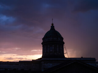 Silhouette of the dome of the Kazan Cathedral in St. Petersburg against the backdrop of sunset thunderclouds
