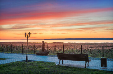 Fototapeta na wymiar pink sunset over Lake Galich in the Kostroma region and a wooden sculpture