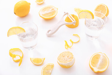 Lemon zest with zester and glasses of water on a white background.