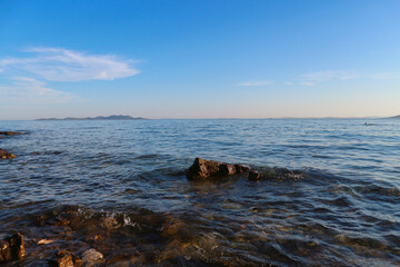 Beautiful dalmatian sea on the Pakostane town beach at sunset, viewing horizon with islands in the distance