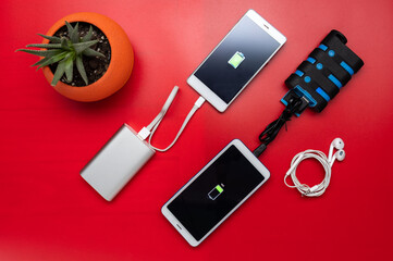 Two jumbled smartphones are charged from power banks. Different smartphones and power banks. Flat...