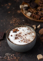 Cup of hot cocoa or hot chocolate with anise star and cinnamon sticks. Traditional beverage for autumn or winter time. Dark textured background.