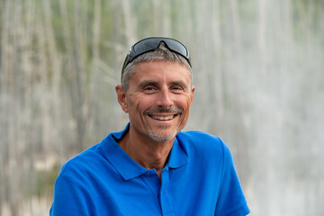 Portrait of happy caucasian male tourist smiling in front of camera outdoor
