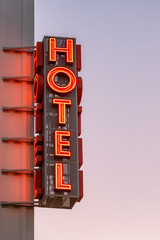 Neon hotel sign on the building corner against the sunset sky