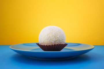 Big Coconut Candy or cake ball With White Chocolate Topping in a plate isolated