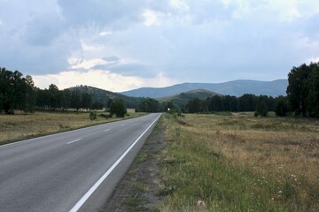 A road in the mountains going far beyond the horizon at sunset