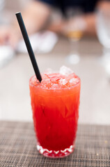 Strawberry lemonade pouring in glass from jug. Cocktail with strawberry, ice and mint in glasses on white concrete background, copy space. Refreshing summer berry drink