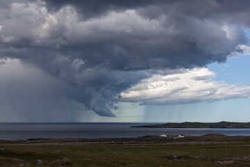 Fototapeta na wymiar Dramatic thunderclouds with rain over Barents sea, Finnmark, Norway