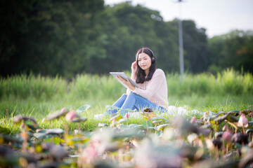 Asian woman is sitting listening to music and smiling with happiness and relaxation. The concept of relaxation with music