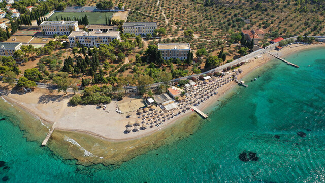Aerial drone photo of organised with sun beds emerald beach of Kaikia in Ligoneri area near old town of Spetses island, Saronic gulf, Greece