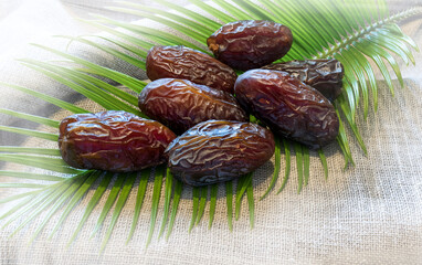 Large royal ripe dates branch of palm leaves with background of textured linen napkin