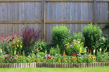 wooden fence with flowers and shrubs.