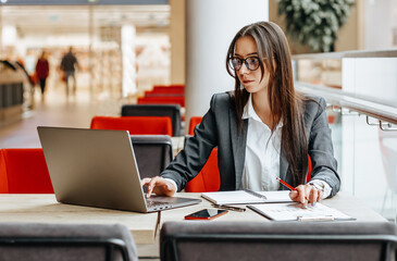 Girl works on a laptop in the workplace. Successful business woman creates a startup and makes decisions.