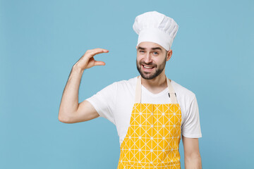 Confused young bearded male chef or cook baker man in apron white t-shirt toque chefs hat isolated on blue background studio portrait. Cooking food concept. Showing blah blah gesture ja jaja hands. © ViDi Studio