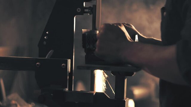 Man sharpening knife with sparks. Work on a sharpening machine