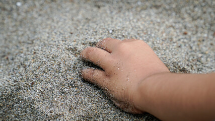 children's hands holding beach sand