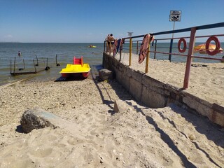 Bright yellow and red catamaran at pier with life jackets and circles on the sea beach