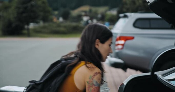 Girl put products from the cart to the car. Young woman shopping fruits and vegetables in a market. Pretty female buy organic and fresh food in the store. Concept of buying, supermarket, health.