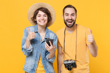 Cheerful young tourists couple friends guy girl with photo camera isolated on yellow background....