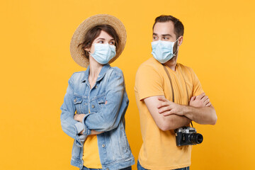 Funny young tourists couple two friends guy girl in sterile face mask isolated on yellow...