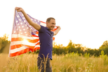 Fourth of July. Patriotic man with the national American flag in the field. Young man proudly waving an American flag. Independence Day.