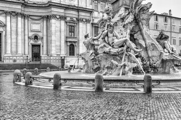 Black and white photo of the Fountain of the Four Rivers in empty Navona Square. Rome. Italy. Horizontally. 