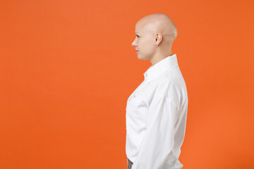 Side view of young bald business woman girl in white shirt posing isolated on orange wall...