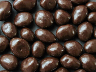 Dark chocolates background, raisins covered with chocolate