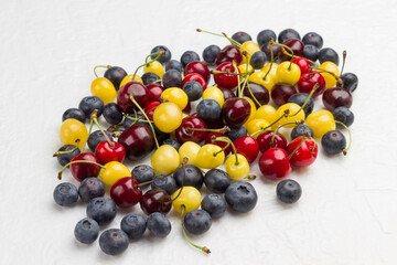Yellow and red cherry, blueberry on white