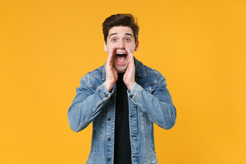 Fototapeta premium Excited young man guy in casual denim jacket posing isolated on yellow background studio portrait. People sincere emotions lifestyle concept. Mock up copy space. Scream with hands gesture near mouth.