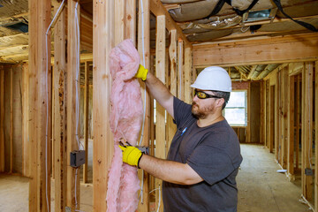 Hand in gloves holding mineral wool, building under construction wall insulation with rock wool