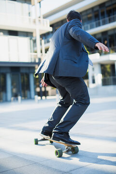 Businessman skateboarding on urban sidewalk