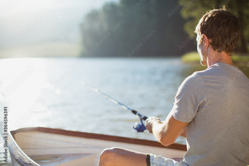 Wall mural Man fishing in rowboat on calm lake