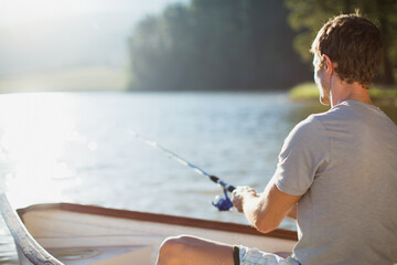 Man fishing in rowboat on calm lake