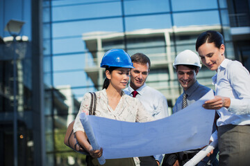 Architects reviewing blueprints outside highrise