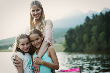 Fototapeta na wymiar Mother and daughters smiling at lakeside