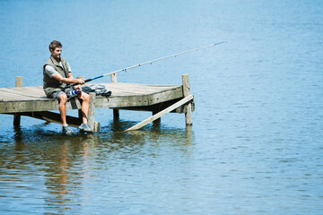Man fishing from dock over lake - Powered by Adobe