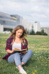 Young pretty woman on the lawn with a book in their hands