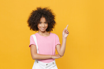 Smiling little african american kid girl 12-13 years old in pink t-shirt isolated on yellow wall...