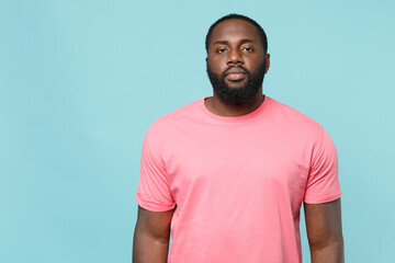 Young african american man guy in casual pink t-shirt posing isolated on pastel blue wall background studio portrait. People sincere emotions lifestyle concept. Mock up copy space. Looking camera.
