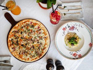 Dinner at an Italian restaurant. White tablecloth, on a pitcher&rsquo;s table with ham and mushrooms and risotto with sea products. Two cold lemonade. Italian traditional food.