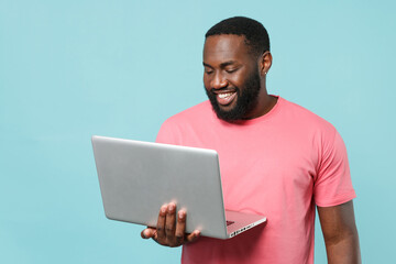 Smiling young african american man guy in casual pink t-shirt isolated on pastel blue wall...
